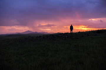 Sunrise landscape with the silhouette of a person, mountains and orange and pink sky, Lesotho, Africa