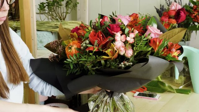 Female florist in flower shop. Woman making a beautiful and stylish bouquet of fresh flowers in floral design studio. 4K