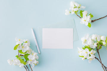 Mockup white wedding invitation and envelope with white flowers on a blue background