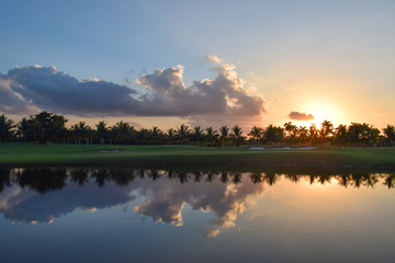 Naklejka na ściany i meble Sunset reflection with clouds and palmtrees