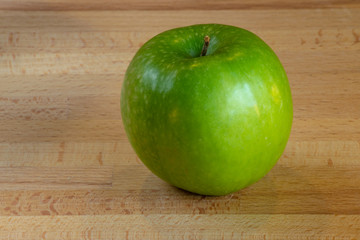 Single isolated green apple on a wooden board