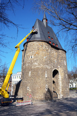 Dachdecker auf Hebebühne untersucht Dacharbeiten mit Schieferplatten als Dachziegel auf Turm von...