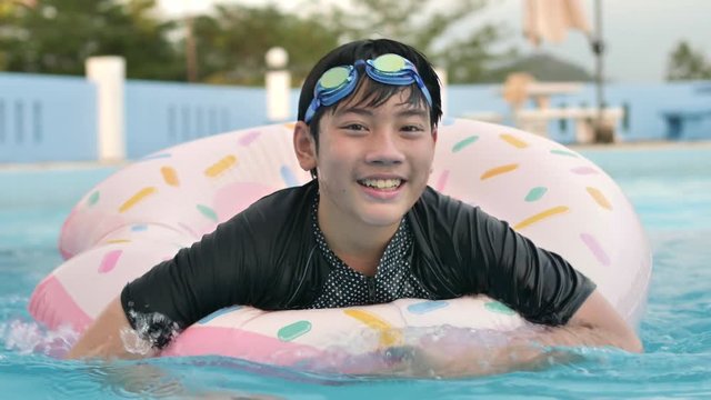 Happy asian child playing in swimming pool with smile fac