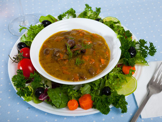 Tasty goulash from chicken hearts with lettuce at plate, fresh vegetables