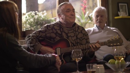 Middle aged man playing guitar for his friends