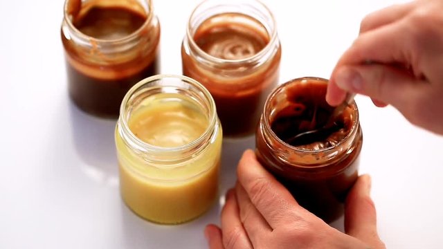 Stirring Milk Caramel Sauce With A Spoon In Glass Jar