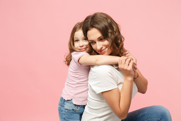 Woman in light clothes have fun with cute child baby girl. Mother, little kid daughter isolated on pastel pink wall background, studio portrait. Mother's Day, love family, parenthood childhood concept