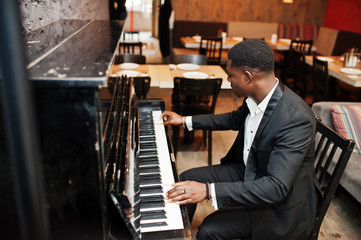 Strong powerful african american man in black suit play piano.