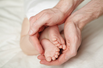 Obraz na płótnie Canvas Dad holding in hands feet of newborn baby