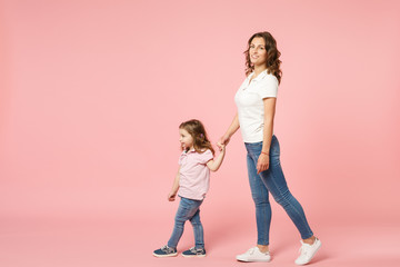 Naklejka premium Kobieta w lekkich ubraniach bawić się z cute dziecko dziewczynka. Matka, córka małe dziecko na białym tle na pastelowym różowym tle ściany, portret studio. Dzień Matki, rodzina miłości, koncepcja dzieciństwa rodzicielstwa