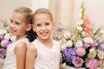 A good young girl in a white dress smiles and relaxes near the mirror at the wedding