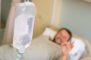 Close-up. Male hand with a dropper during chemotherapy in a hospital. The man is in the hospital room, without focus. Health is a topic of health and healing.