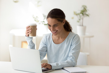 Woman at work typing message on laptop smiling