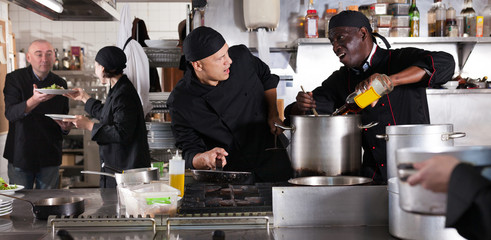 Chef with team preparing food in kitchen of restaurant
