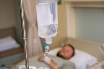 Close-up. Male hand with a dropper during chemotherapy in a hospital. The man is in the hospital room, without focus. Health is a topic of health and healing.