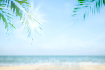 Fototapeta na wymiar Abstract soft blur nature tropical beach with green coconut palm leaf and light wave bokeh background concept for blurry sky summer landscape water and sand, holiday ocean travel, relax vacation day