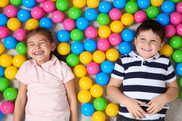Fototapeta na wymiar Cute children lying on floor near colorful balls, top view. Playing indoors