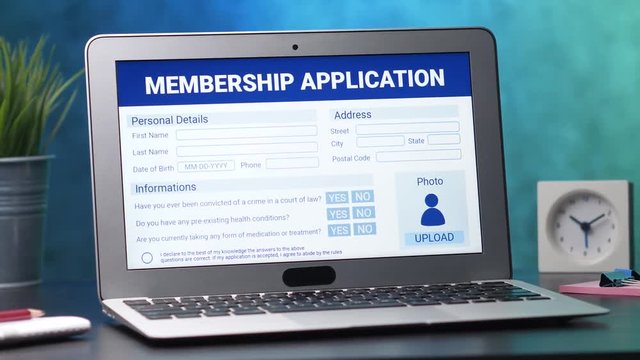 Laptop computer with a membership application form on its display. Camera turning slowly around the desk.