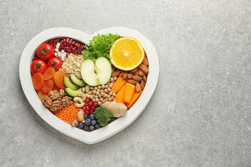 Heart shaped tray with healthy products on grey background, top view. Space for text