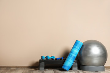 Set of fitness inventory on floor near color wall. Space for text