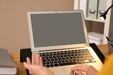 Fototapeta premium Young woman using modern laptop at table, closeup