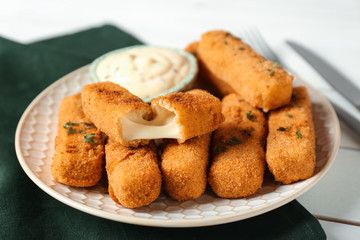 Plate of cheese sticks with sauce on table, closeup