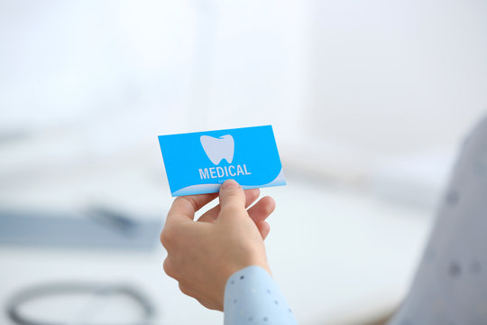 Woman holding business card indoors, closeup. Dental medical service