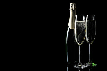 Bottle and glasses of champagne on black background, space for text