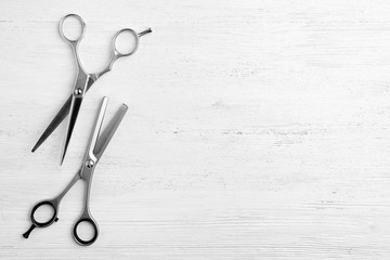 Flat lay composition with scissors and space for text on white wooden background. Hairdresser tools
