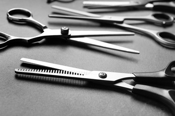 Many scissors on grey background, closeup. Hairdresser tools