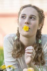Portrait of a girl with pigtails among yellow dandelions close-up.