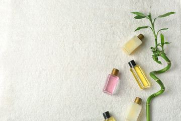 Mini bottles with cosmetic products on towel, top view and space for text. Hotel amenities
