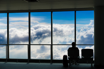 silhouette of business tourist people with luggage looking at blue sky with clouds and and waiting at the plane boarding gates before departure in airport, travel, lifestyle and transportation concept