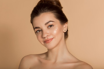 Beautiful face portrait of young woman with moisturizing face cream on a cheek. Skin care and health concept.