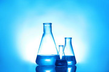 Laboratory glassware with liquid on color background. Solution chemistry