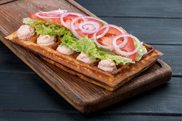 Belgian waffle with salmon cream, tomatoes and salad. On a dark wooden background