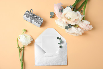 Fototapeta na wymiar Flat lay composition with beautiful ranunculus flowers and card in envelope on color background. Space for text