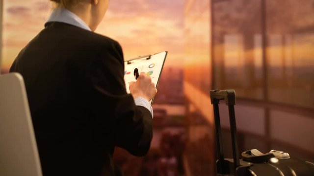 Flight attendant checking documentation before flight, sitting at airport
