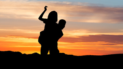 Couple at sunset. Silhouette of man piggybacking his girlfriend