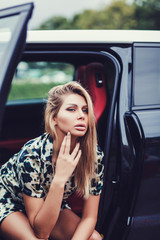 beautiful stylish girl in dress posing in car