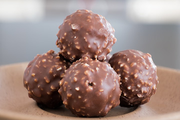 Chocolate & Crushed Almond Crispy Balls on a Light Brown Serving Plate and in Natural Light