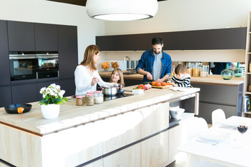 Beautiful cute family having fun while cooking together in the kitchen at home.