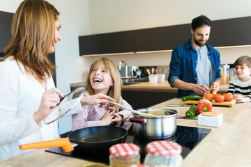Beautiful cute family having fun while cooking together in the kitchen at home.