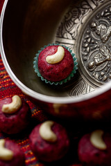 Red vegan candy with nuts, raw food truffles, decorated with cashew nuts on a beautiful silver plate close-up.