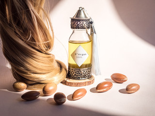 Curll hair of golden hair and decorative bottle with iron embossed in traditional Moroccan style with precious Moroccan argan oil and nuts ander natural lighting of sun with hadows frame