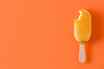 Bitten orange popsicle pattern on orange background. Top view. Copyspace