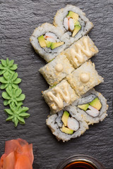 Uramaki sushi with surimi crab, avocado served on black stone