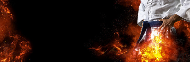 Guy poses in white kimono with black belt. Flame background © Andrey Burmakin
