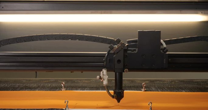 In an industrial garment factory, a special Laser Cutting Fabric cuts out certain textile pieces. Concept of: Laser machine, Crosses, Work in a factory, Automatic cutting.