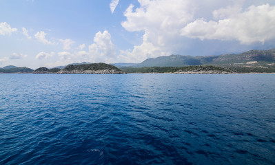 a view of the yacht on the blue waters and the various mountain scenery on the blue sky; travel pleasure in summer